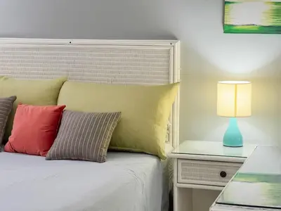 a bed with colorful pillows and a table with a lamp at Garden Condos APT 44 - Comfy 1BR APT in Sosua in Sosúa