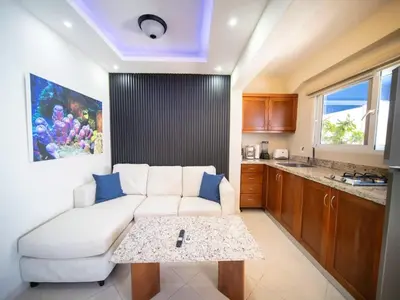a living room with a white couch and a table at Casa de Compai Studio 1 AC WiFi Prime Location in Sosúa