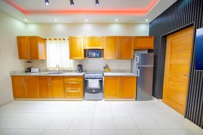 a kitchen with wooden cabinets and stainless steel appliances at Stylish 1BR in Sosua Walkable & Pool Fast WIFi in Sosúa