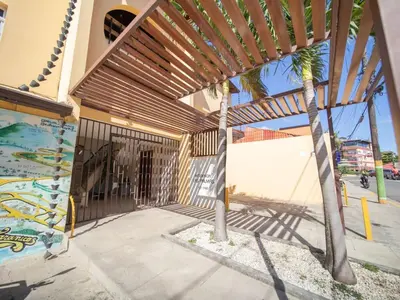 a wooden pergola on a building with a palm tree at Colonial 2BR Apartment 2 mins walk to beach in Sosúa