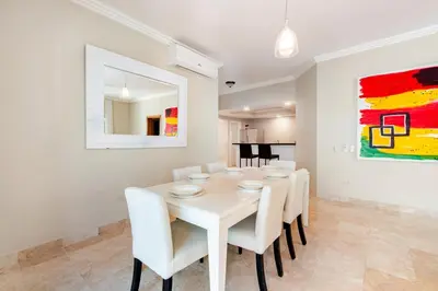 a white dining room with a white table and chairs at Large apartment at the foot of the beach in Punta Cana