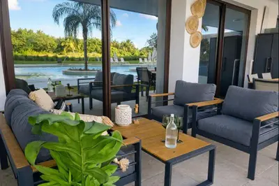 a patio with couches and tables and a view of the water at Aqua Poolside Serenity Pool & Golf 2B Cana Bay in Punta Cana
