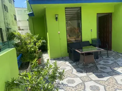 a patio with a table and a green wall at Casa Gadlu Hotel in Santo Domingo