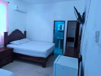 a bedroom with a bed and a dresser and a mirror at Casa Gadlu Hotel in Santo Domingo