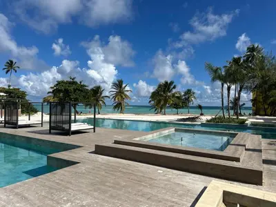 a swimming pool with the ocean in the background at Alexger Beachfront Apartament Bavaro, Punta Cana in Punta Cana