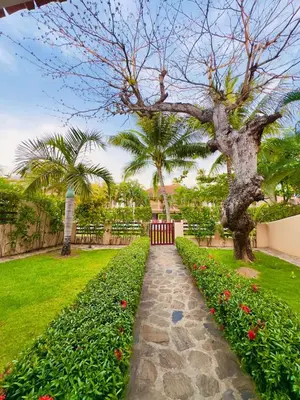 a walkway in a park with a tree and flowers at Family Villa Terrenas Samana Near the Beach in Las Terrenas