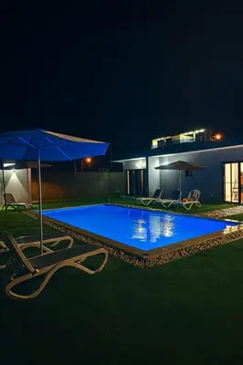a swimming pool with chairs and an umbrella at night at Ivy Villa Cabarete, fully equipped villa in Cabarete