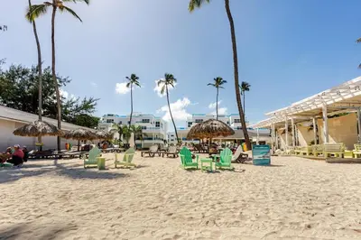 a sandy beach with chairs and umbrellas and palm trees at First Line, Direct Access to Private Beach in Punta Cana