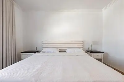 a white bedroom with a large white bed with two night stands at First Line, Direct Access to Private Beach in Punta Cana