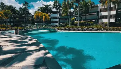 a large swimming pool with a bridge in front of a building at Oceanfront PH Jacuzzi Balconies of the Atlanti in El Limón