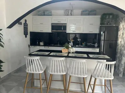 a kitchen with white stools and a counter with a refrigerator at Alma Stay Central and cozy in Santa Bárbara de Samaná