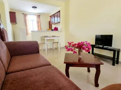 a living room with a couch and a table with flowers on it at 2-Bedroom Beach Apartment 50m from the Sea and Pool in San Felipe de Puerto Plata