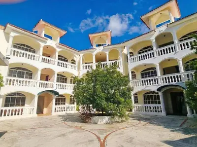 a large white building with a tree in the courtyard at 2-Bedroom Beach Apartment 50m from the Sea and Pool in San Felipe de Puerto Plata