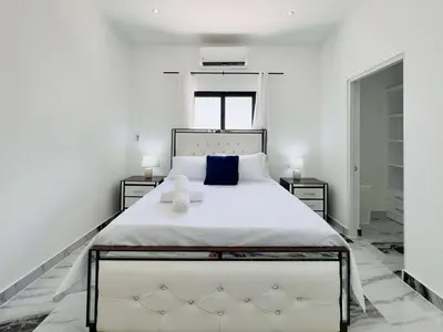 a bedroom with a large white bed with blue pillows at Villa Las Terrenas Cosón minutes Pool and AC in Las Terrenas