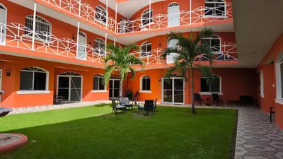 an orange building with chairs and trees in the courtyard at 1BR Studio with Pool, Fast Wi-Fi, Walk to Beach in Sosúa