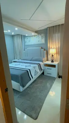a bedroom with a large bed and a table with a lamp at D Gomez House in Santiago de los Caballeros