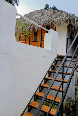 a staircase leading up to a house with a thatch roof at Mejor, Quédate Aquí in Las Galeras
