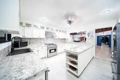 a kitchen with white cabinets and marble counter tops at Villa Reme 19 in La Romana