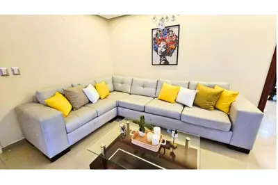 a living room with a blue couch with yellow pillows at Cubana Stays in Santiago de los Caballeros