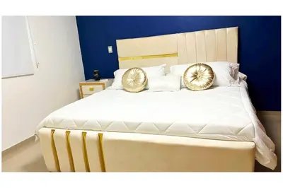 a bedroom with a large bed with two gold pillows at Cubana Stays in Santiago de los Caballeros