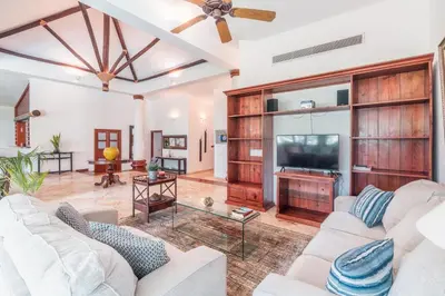 a living room with white furniture and a flat screen tv at Comfortable villa with garden view and 3 bedrooms in Cajuiles