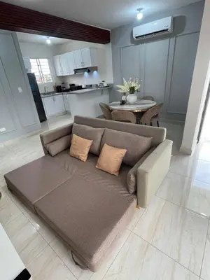 a living room with a couch and a kitchen at Apartamento acogedor en Santo Domingo este in Hainamosa
