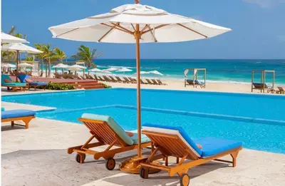 a pair of chairs and an umbrella next to a swimming pool at Luxury 2BR, Private Jacuzzi, CanaRock Star in Punta Cana