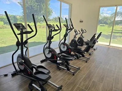 a row of exercise bikes in a gym with a large window at Luxury 2BR, Private Jacuzzi, CanaRock Star in Punta Cana