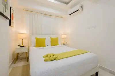 a bedroom with a large white bed with yellow pillows at Cozy 3BR Condo in Ens. Ozama in La Cruz de Mendoza