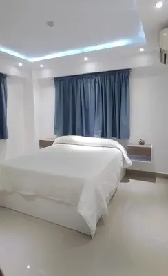 a bedroom with a white bed with blue curtains at Apartamento con tres habitaciones, piscina y parking techado gratis in Juan López