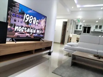 a living room with a tv and a white couch at Apartamento con tres habitaciones, piscina y parking techado gratis in Juan López