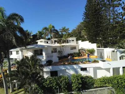 a white house with palm trees in front of it at Puerto Plata, beach Pent house in Maggiolo