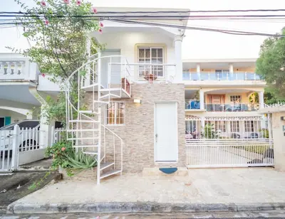 a brick house with a white door and a spiral staircase at Studio in Sosua Center Near Sosua beach in Sosúa