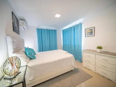 a bedroom with a large bed with blue curtains at Cozy & Central 3BR Apt Secure & Comfortable in Sosúa