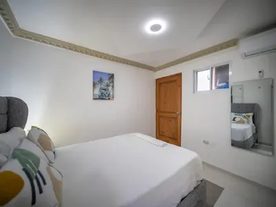 a bedroom with a white bed and a wooden door at Room in the center with Outdoor Jacuzzi in Sosúa