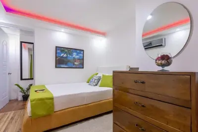 a bedroom with a bed and a mirror and a dresser at Getaway room with shared Jacuzzi in the center in Sosúa