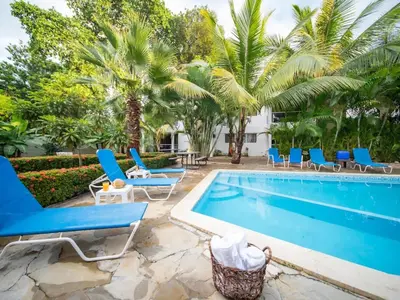 a pool with blue chairs and palm trees at Affordable 1BR APT in Sosua Center - Strip Zone in Sosúa