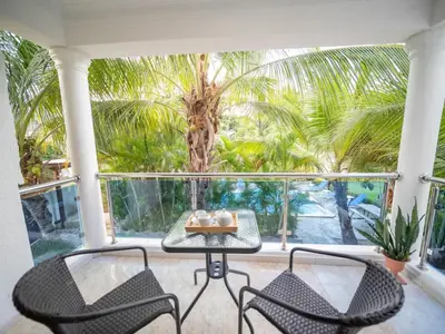 a table and chairs on a balcony with a palm tree at Affordable 2BR APT in Sosua Center in Sosúa