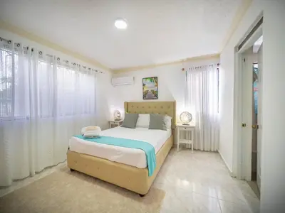 a bedroom with a bed with white walls and windows at Affordable 2BR APT in Sosua Center in Sosúa