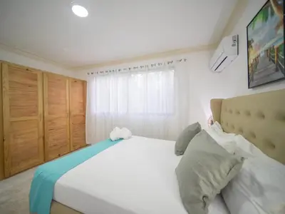 a bedroom with a large white bed and a window at Affordable 2BR APT in Sosua Center in Sosúa