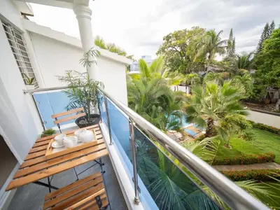 a balcony with a wooden bench and palm trees at 2BR APT in Sosua Center Strip zone in Sosúa