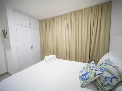 a bedroom with a white bed and a curtain at 2BR APT in Sosua Center Strip zone in Sosúa