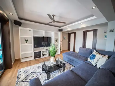 a living room with a blue couch and a tv at 4BR Penthouse with Rooftop Pool in Sosua strip in Sosúa