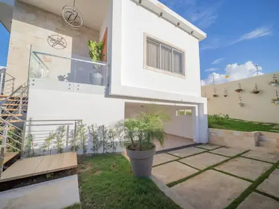 a white house with a potted plant in the yard at Stylish Luxury Villa in Sosua- 5BR Suites in Sosúa