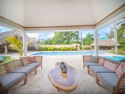 a patio with couches and a table and a pool at Sun and Soul Caribbean 9BR Villa in Sosua in Sosúa