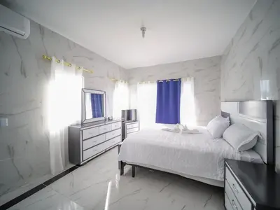 a white bedroom with a bed and a television at 8BR Private Villa in Sosua 2 mins from Nightlife in Sosúa