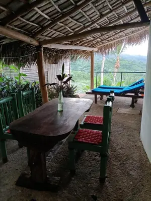 a wooden table and chairs under a roof with a table and chairs at villa vue mer in Las Terrenas