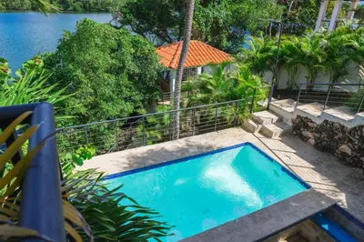 a swimming pool in a yard next to the water at La casa del lago in Cumayasa