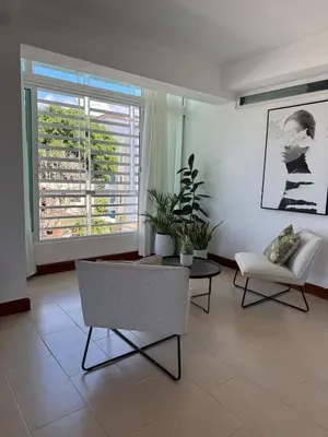 a living room with chairs and a table and a window at Moderno y Acogedor Apartamento detrás del Homs in Santiago de los Caballeros