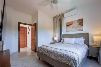 a bedroom with a bed and a dresser and a door at A Tropical Oasis - Vista Canas Villa Vista in Punta Cana